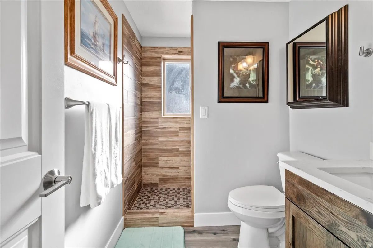 Bathroom with vanity, tiled shower, and light wood-style flooring
