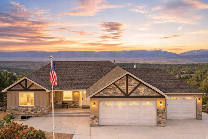 View of front of home featuring stone siding, an attached garage, driveway, and a mountain view