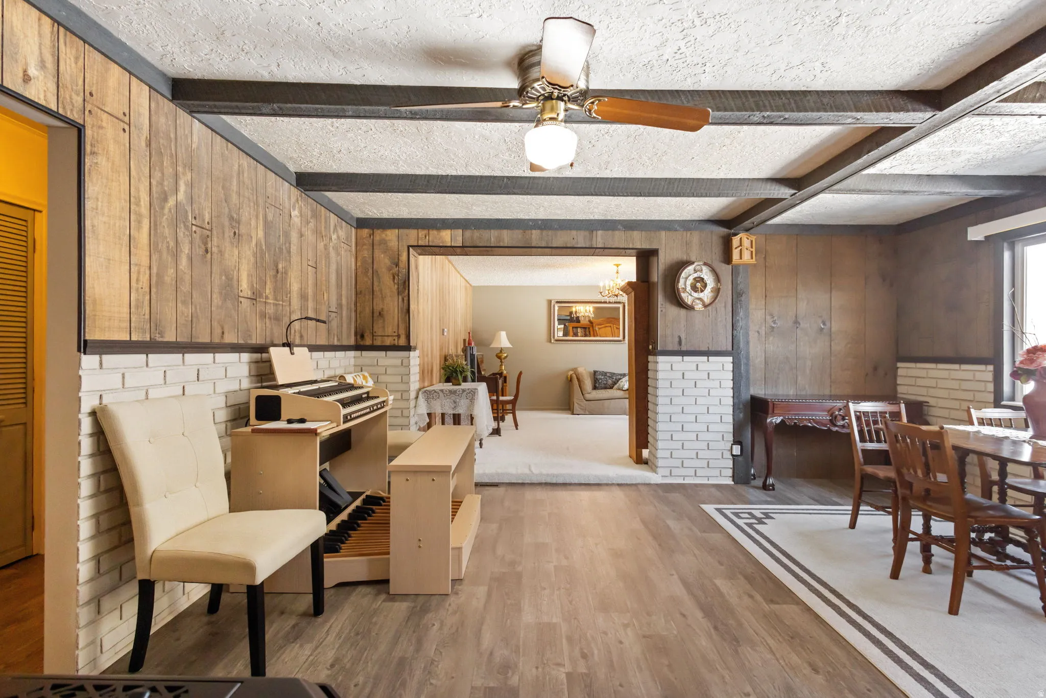 Dining area with a textured ceiling, beamed ceiling, light wood finished floors, and ceiling fan