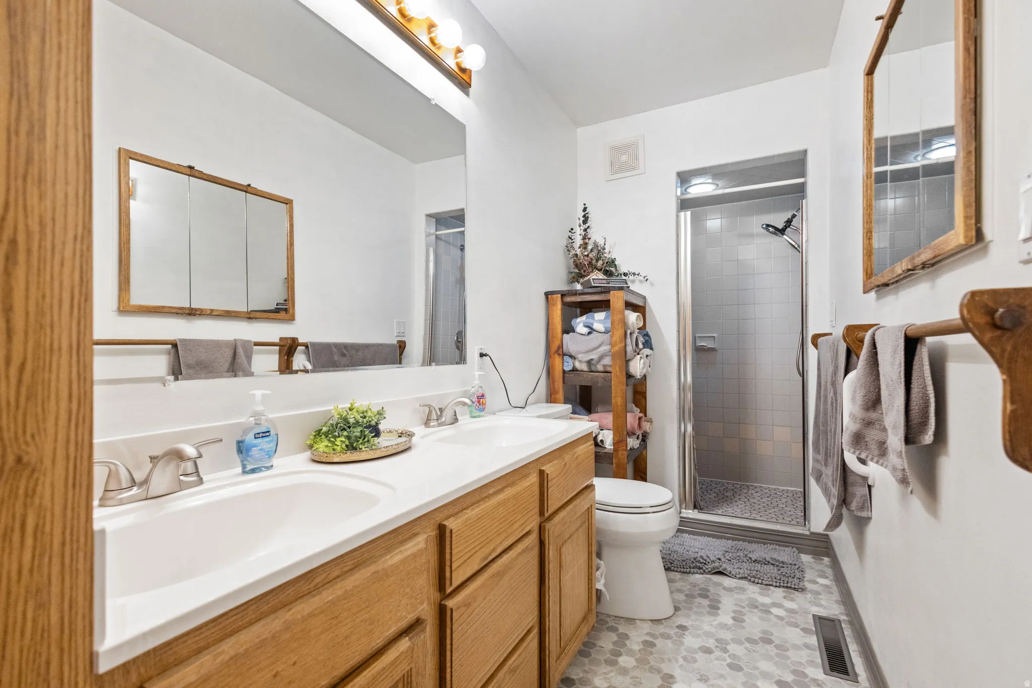 Full bath with double vanity and a shower stall