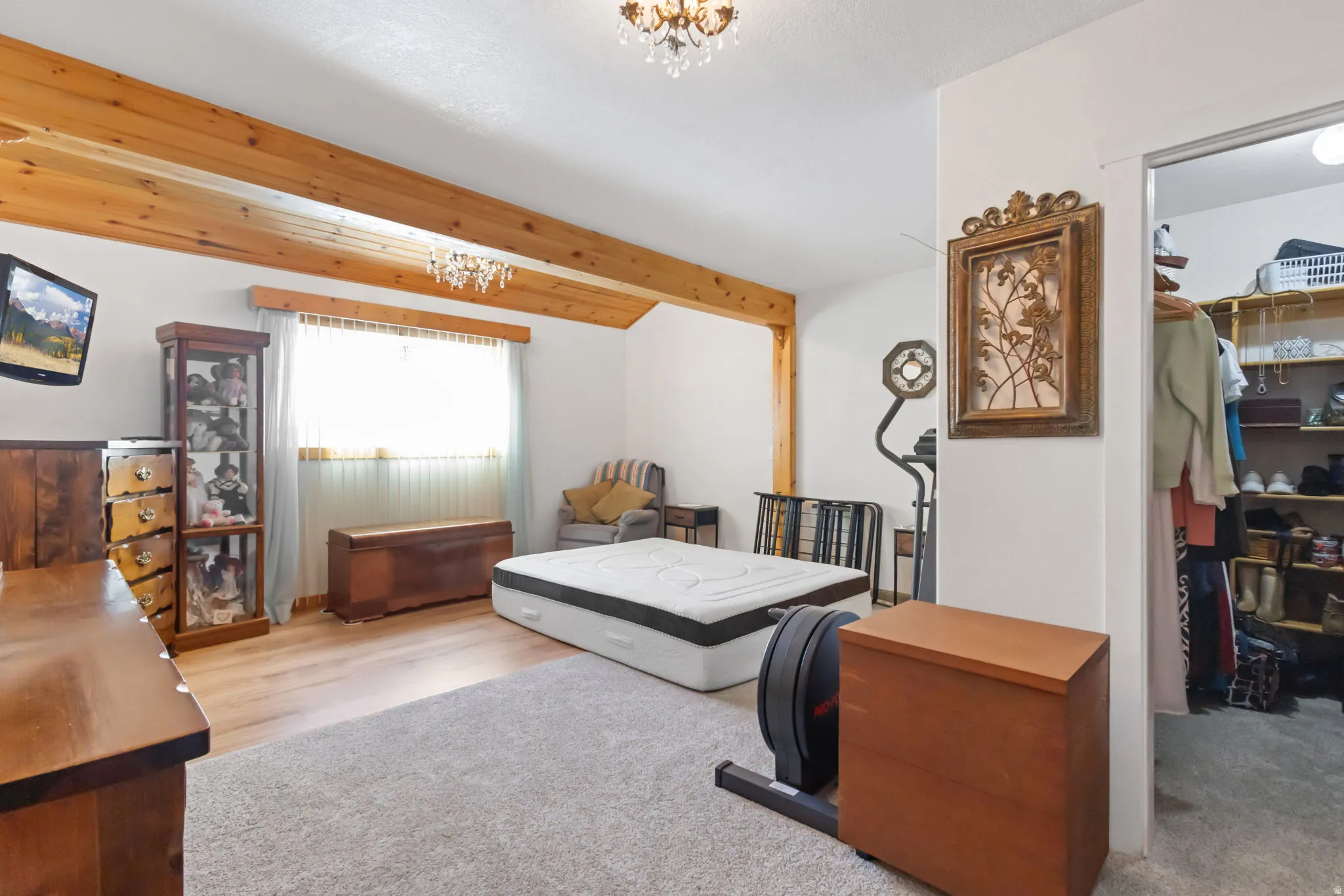 Bedroom with hanging lights, beamed ceiling, and a spacious closet