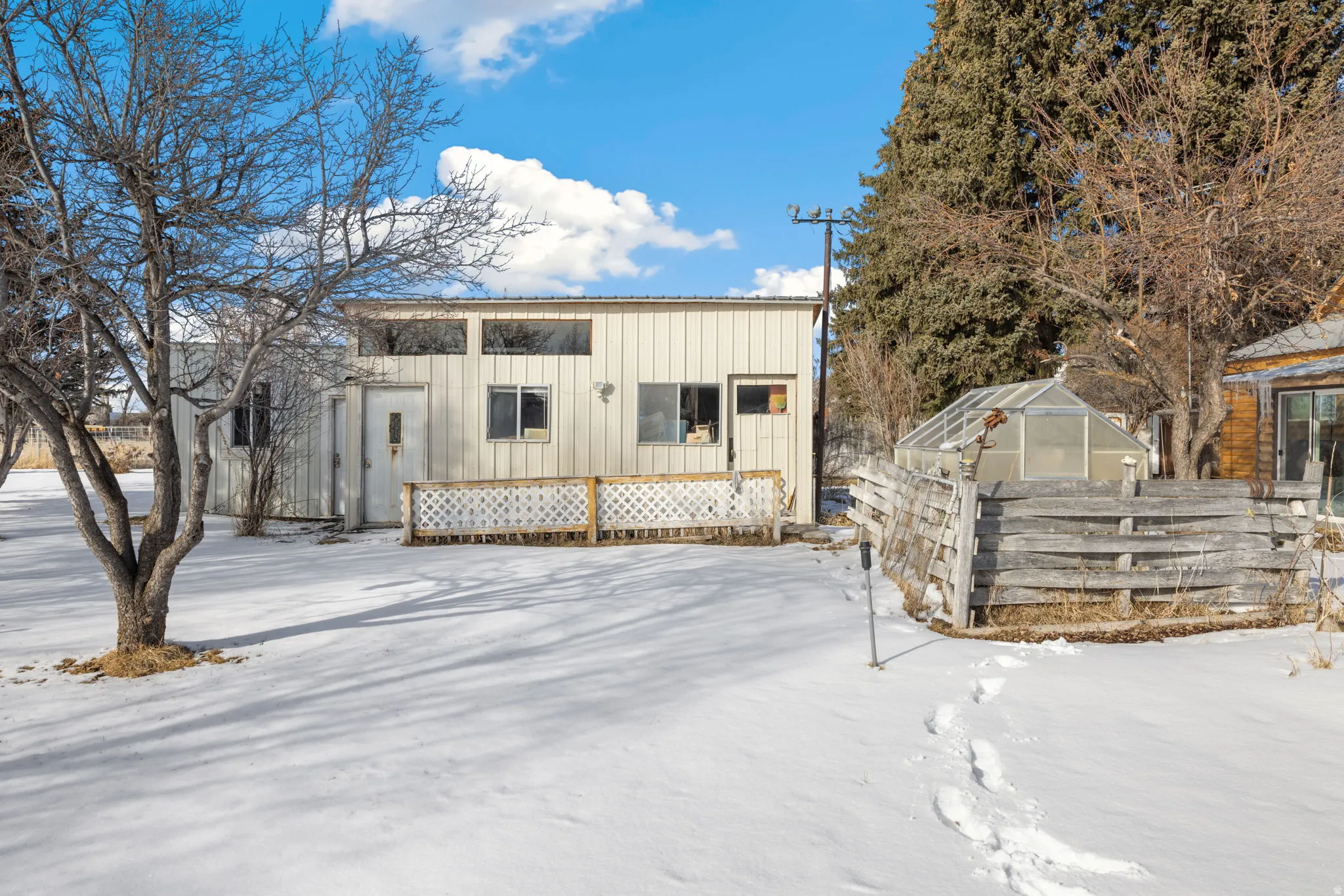 View of front of home featuring an outbuilding, a greenhouse, and board and batten siding