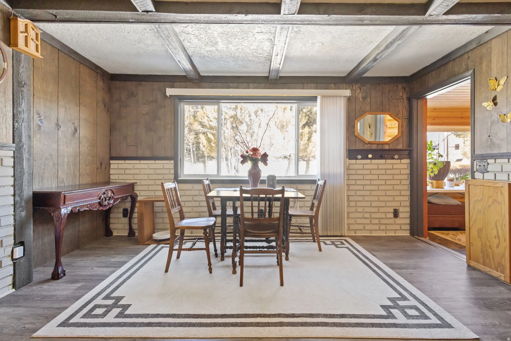 Dining room with wood walls, wood finished floors, and beamed ceiling