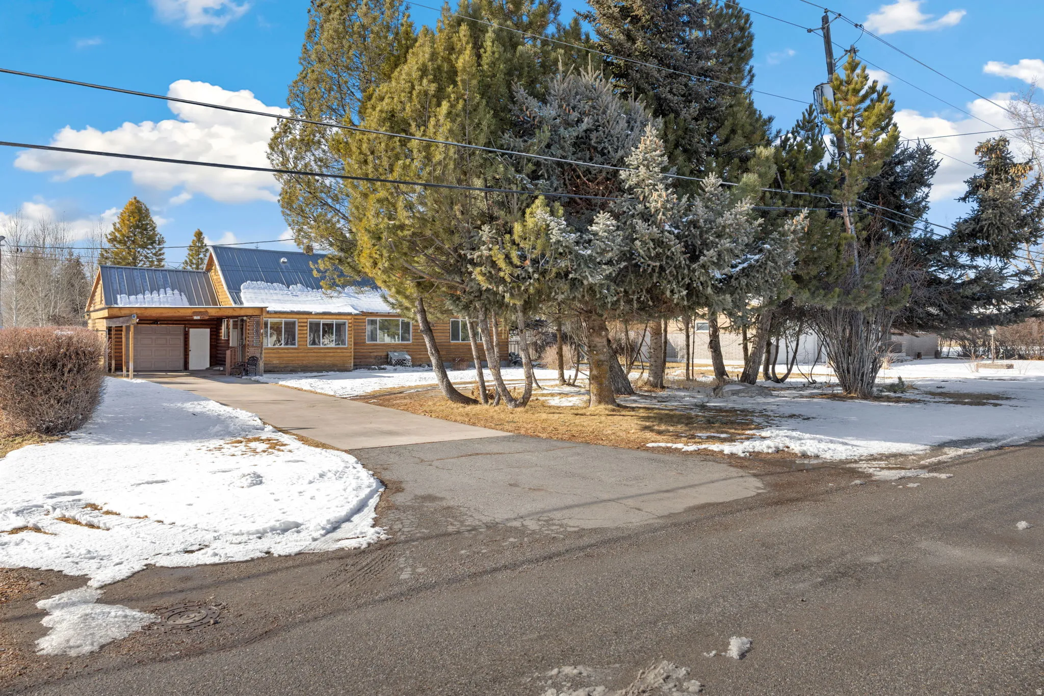 View of front of property featuring driveway, a garage, roof mounted solar panels, and a metal roof