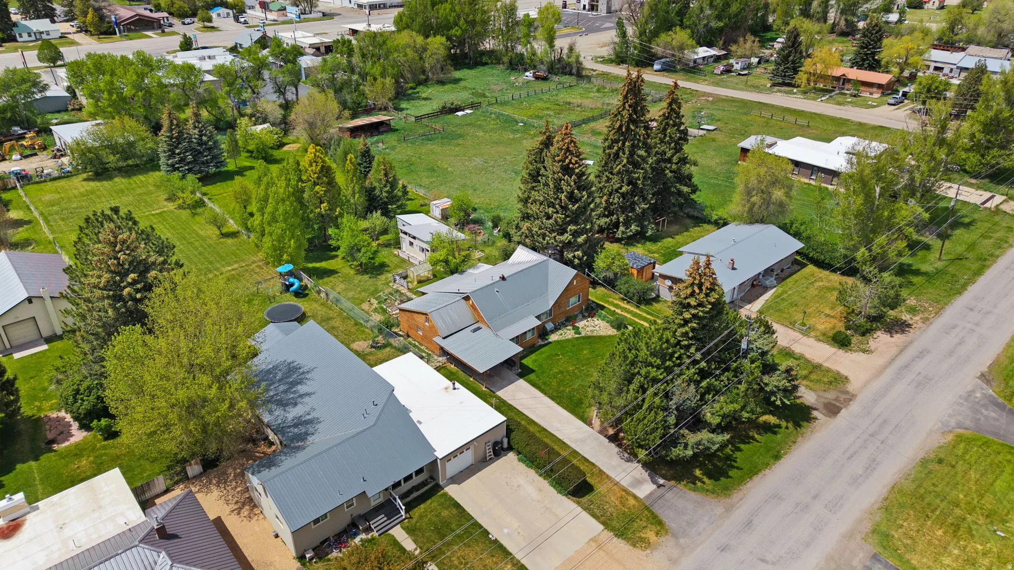 Expansive property featuring three distinct residences, multiple outbuildings, mature trees, and a spacious green area
