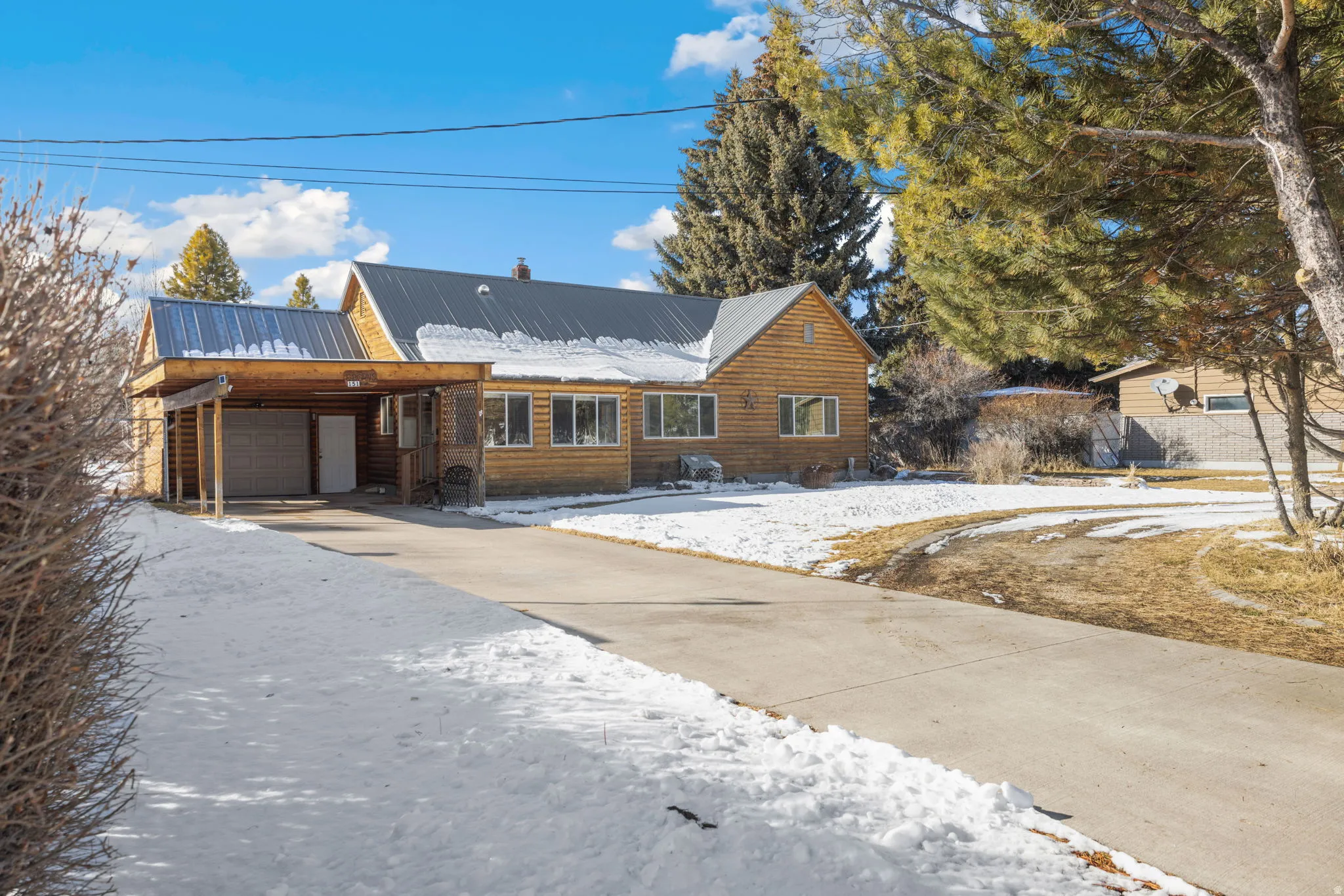 Chalet / cabin with a metal roof, driveway, and a garage