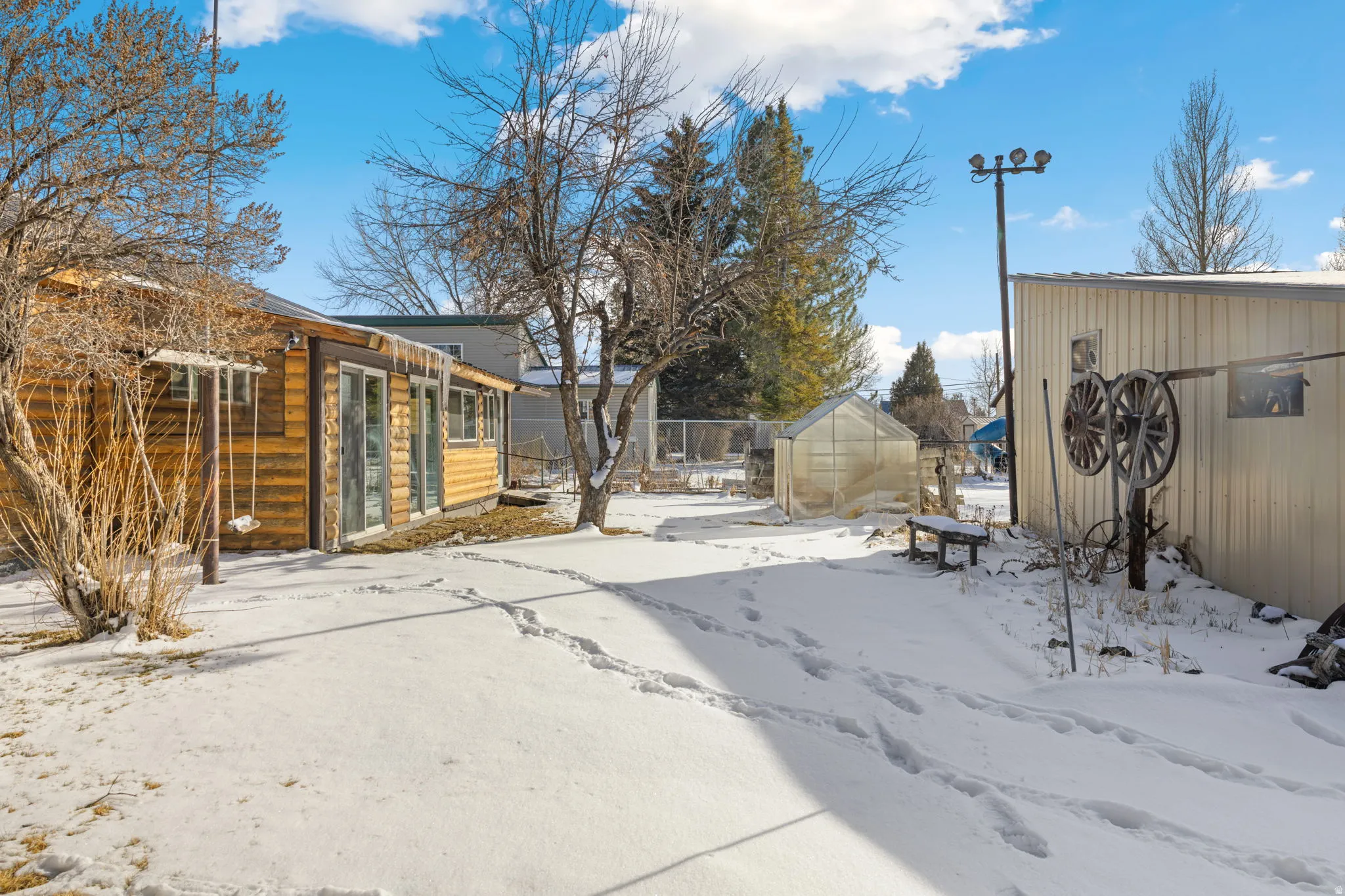 Snowy yard with a greenhouse and an outbuilding