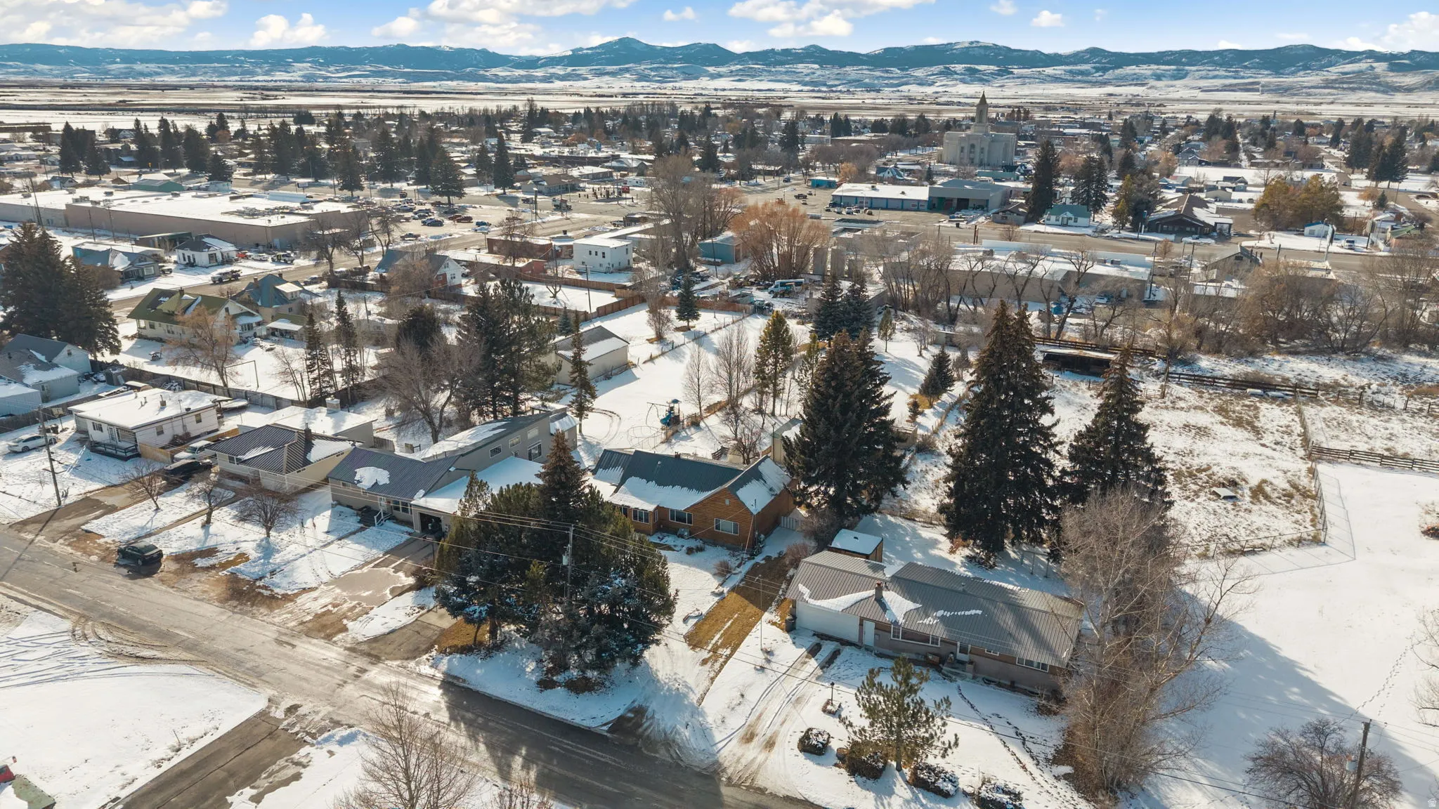 Snowy aerial view featuring a mountain view and a residential view