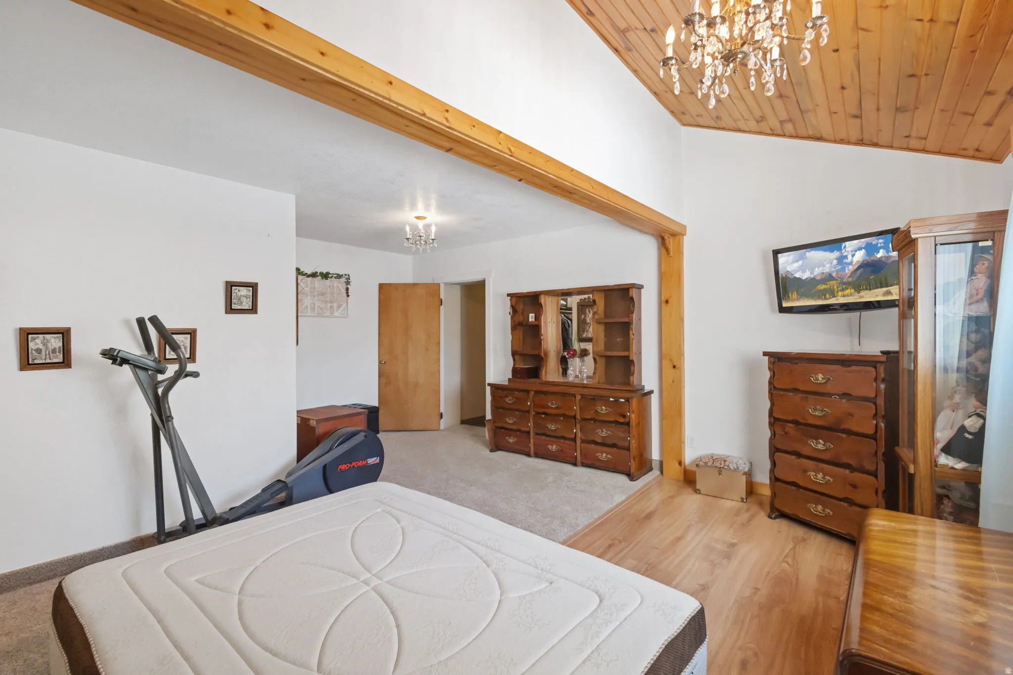 Bedroom featuring hanging lights, light wood finished floors, and a vaulted wooden ceiling