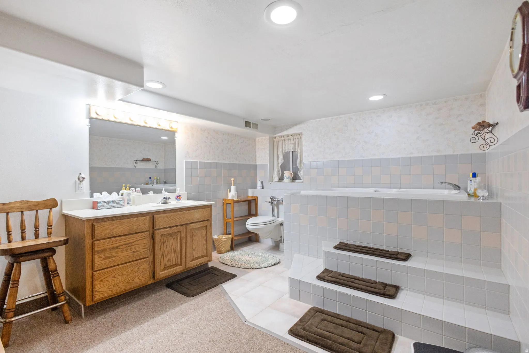 Full bath featuring vanity, a bath, tile walls, a wainscoted wall, and recessed lighting
