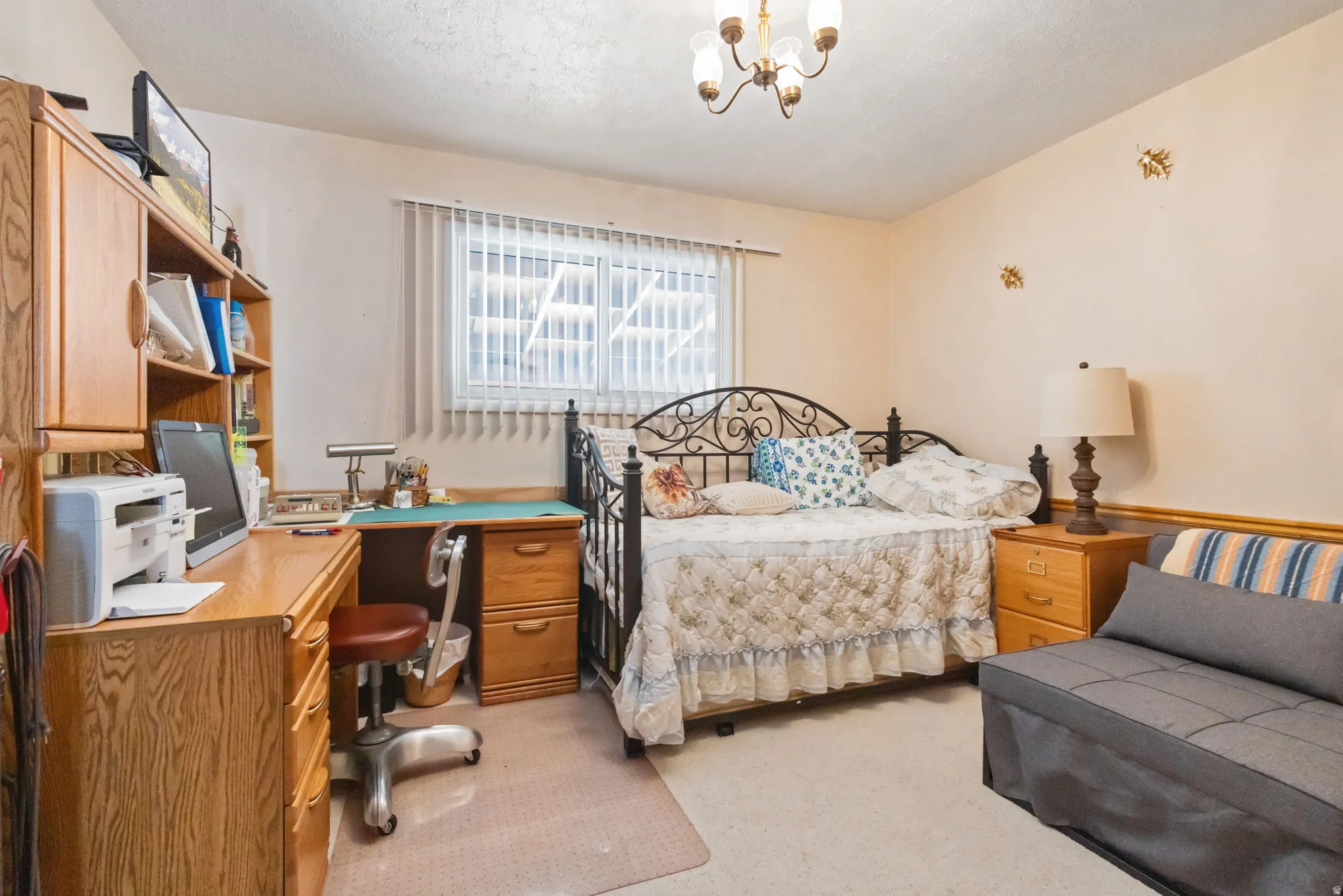 Bedroom with light carpet, an office area, and suspended lighting