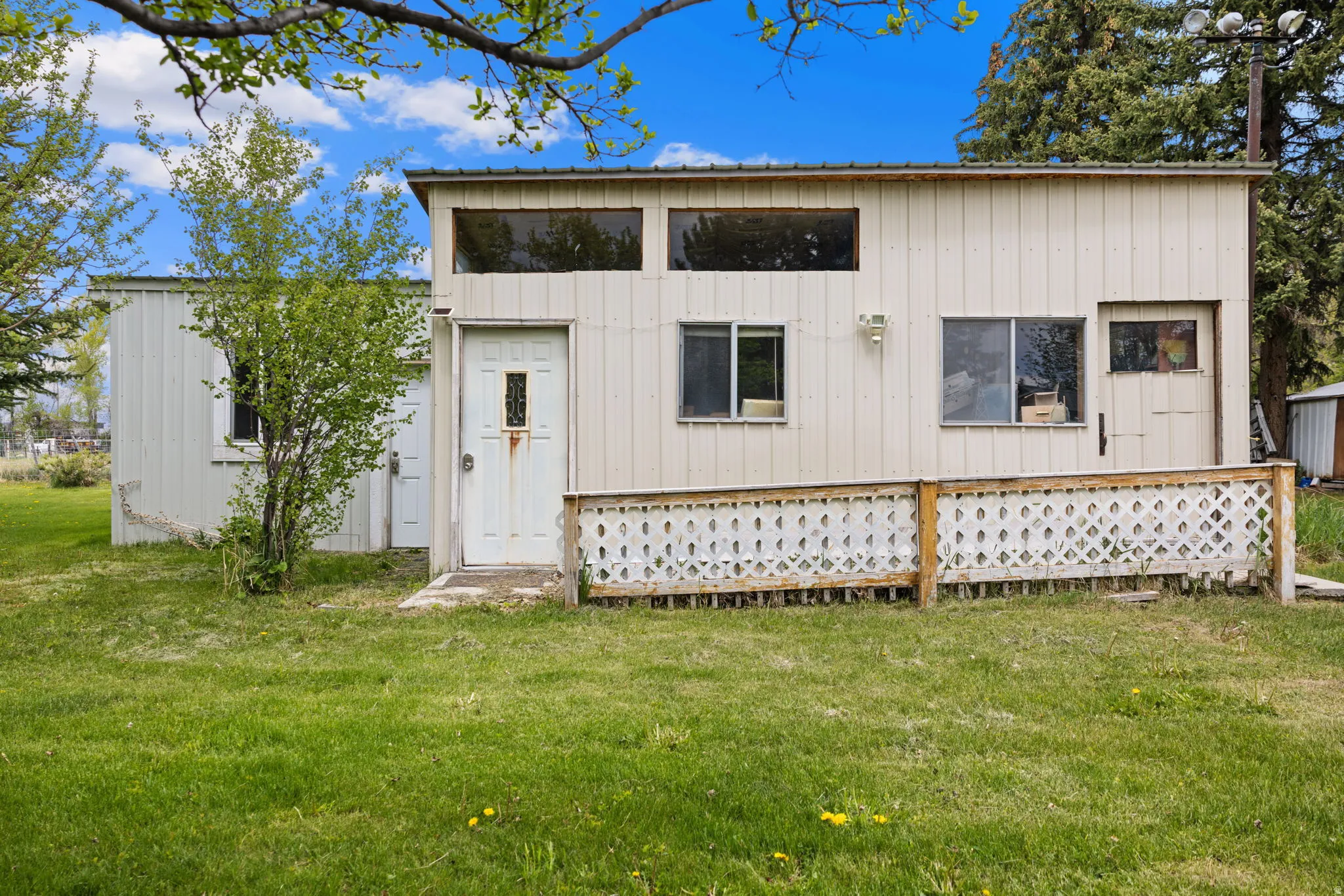 Exterior structure featuring vertical siding, multiple window styles, and a white entry door