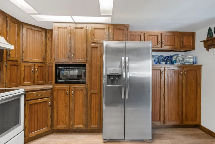 Kitchen featuring stainless steel fridge with ice dispenser, wood finish cabinetry, white range with electric cooktop, and black microwave