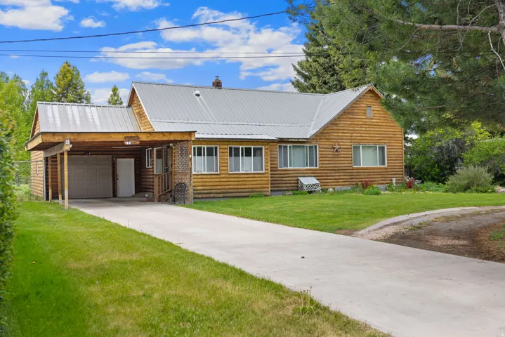 Log-sided residence featuring a carport, attached garage, and a concrete driveway