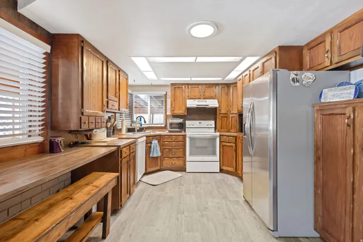 Kitchen featuring white appliances, wood finish cabinetry, and light wood-type flooring