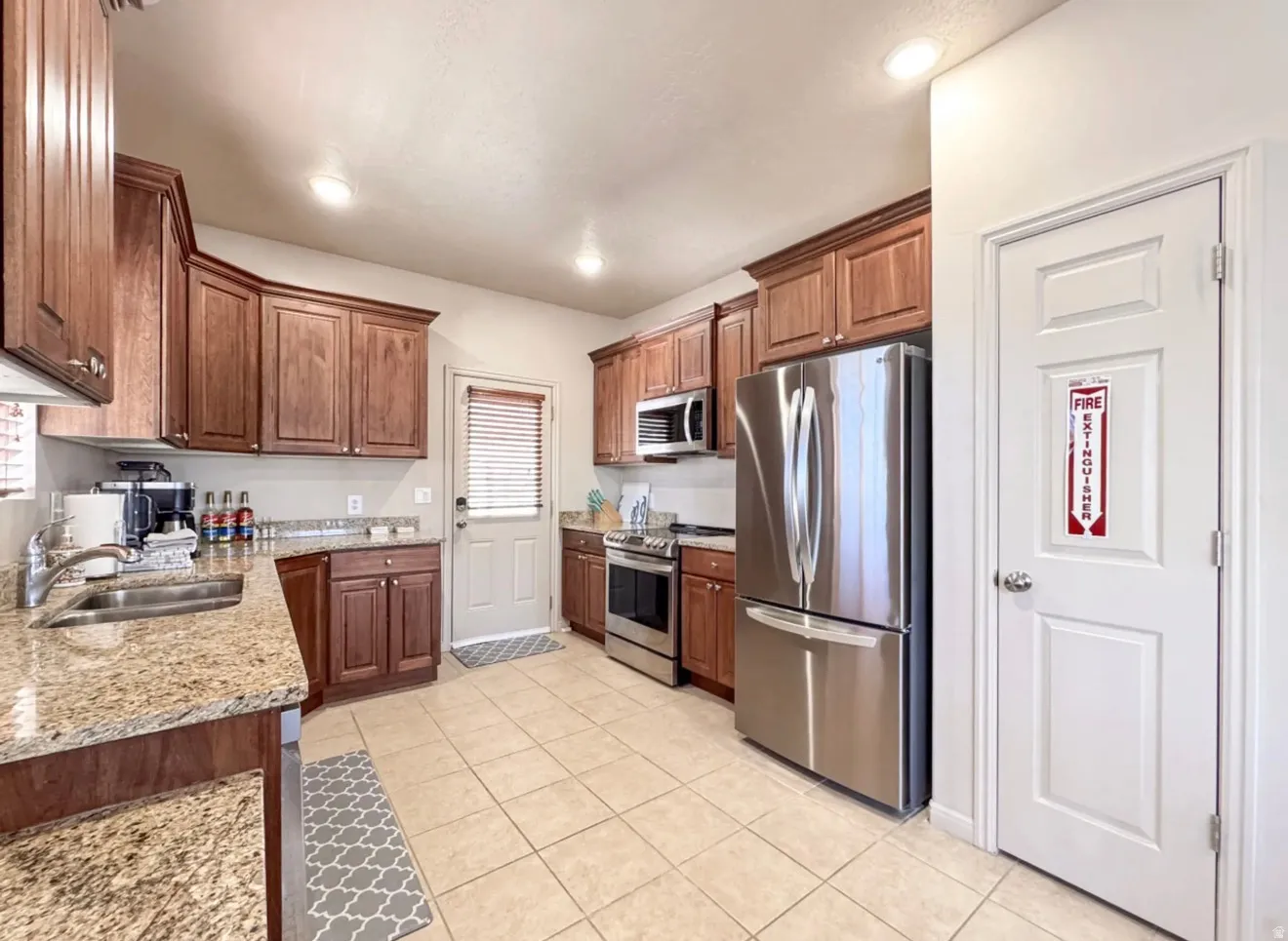 Kitchen with stainless steel appliances, light stone countertops, light tile patterned floors, wood finish cabinetry, and recessed lighting