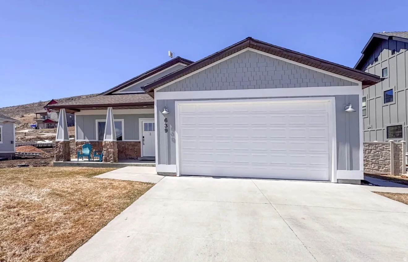 View of front of home with a garage, driveway, a porch, and stone siding