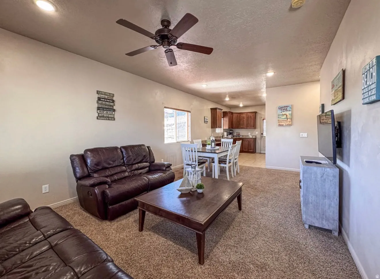 Living room with a ceiling fan, light colored carpet, a textured ceiling, and recessed lighting