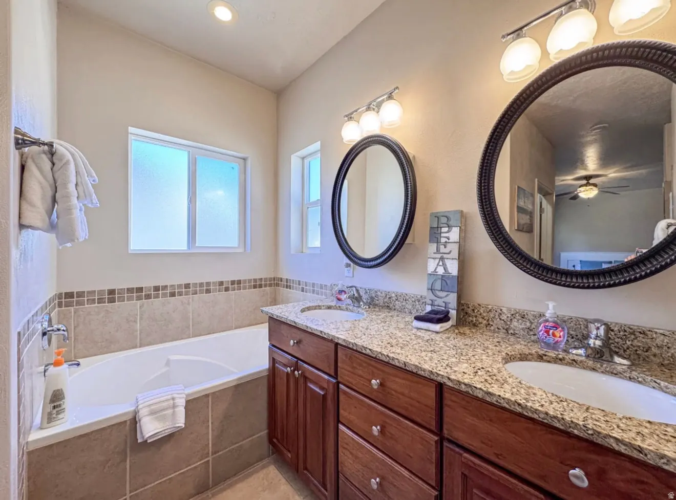Bathroom featuring double vanity, a bath, and a ceiling fan
