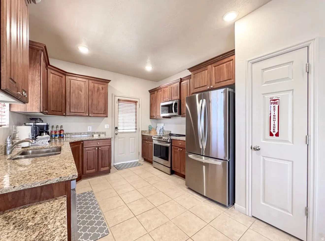 Kitchen featuring stainless steel appliances, light stone countertops, light tile patterned floors, recessed lighting, and wood finish cabinetry