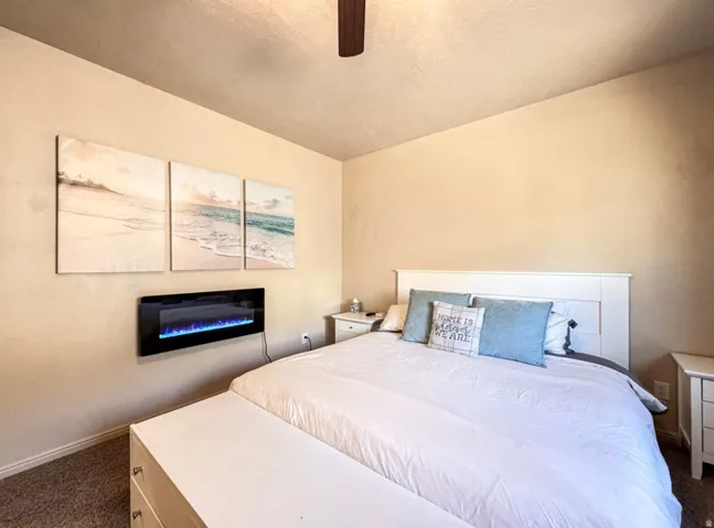 Bedroom with dark carpet and a ceiling fan