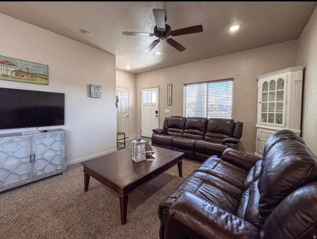 Living room with a ceiling fan, a textured ceiling, and carpet flooring