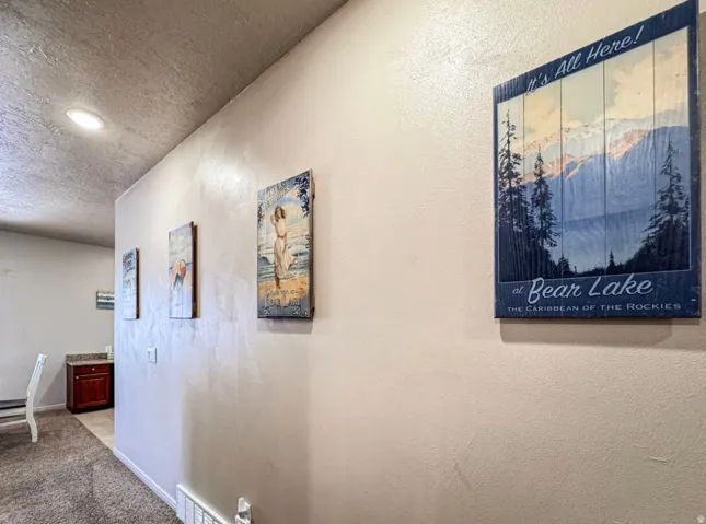 Hall featuring a textured ceiling, carpet, recessed lighting, and a textured wall