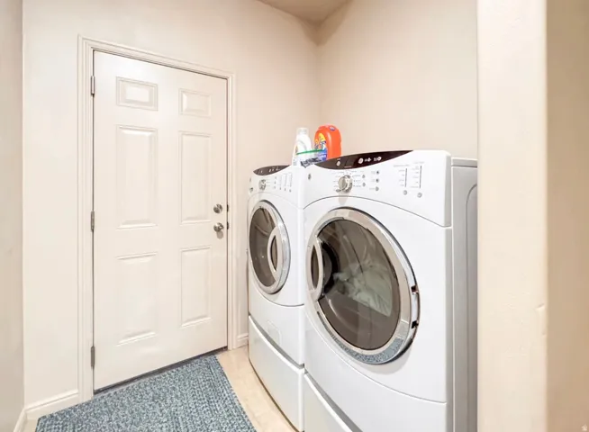 Laundry area featuring washer and dryer and light tile patterned floors