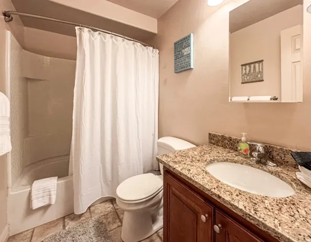 Full bath with vanity, stone tile floors, and shower / tub combo