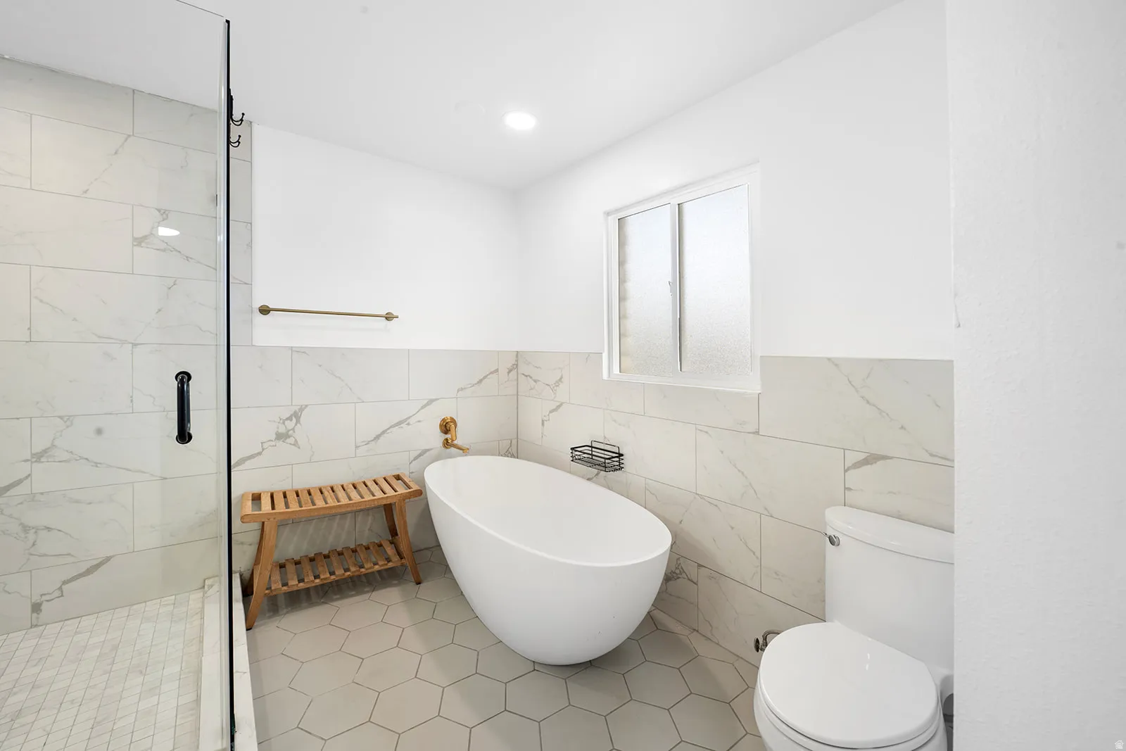 Bathroom with a marble finish shower, a soaking tub, tile walls, light tile patterned floors, and a wainscoted wall