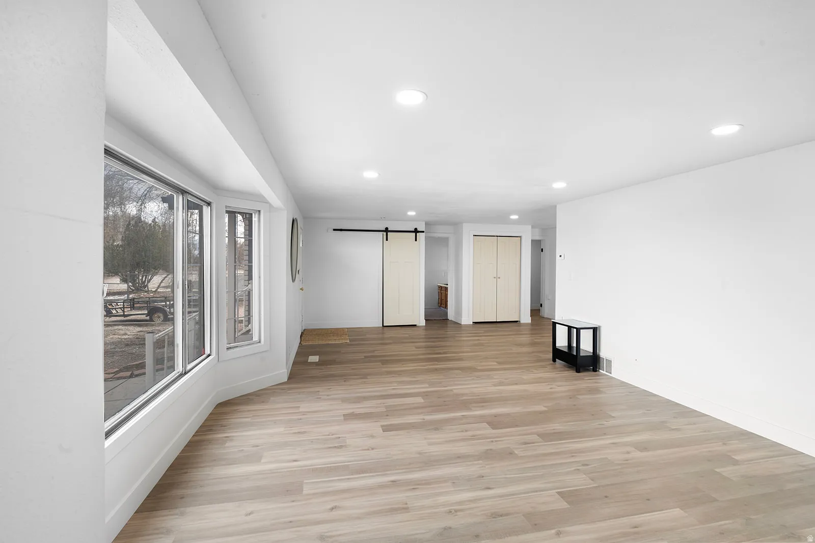 Spare room featuring a barn door, light wood finished floors, and recessed lighting