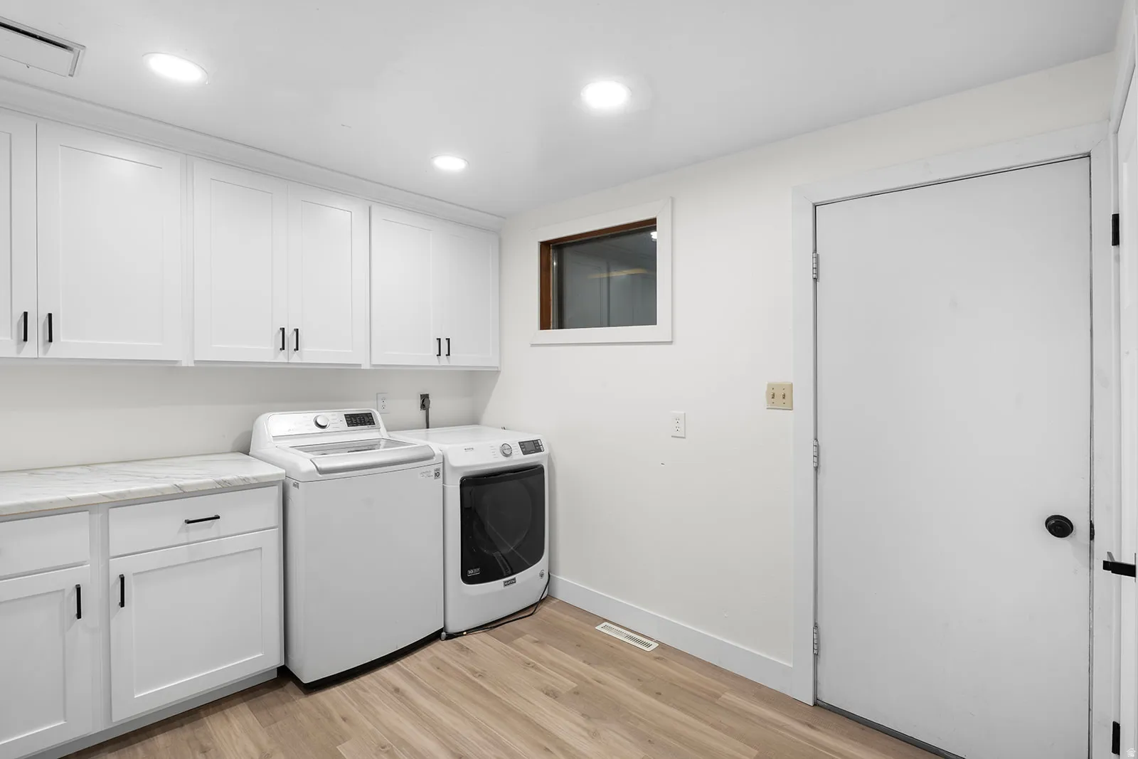 Laundry area with light wood-style flooring, washer and clothes dryer, cabinet space, and recessed lighting