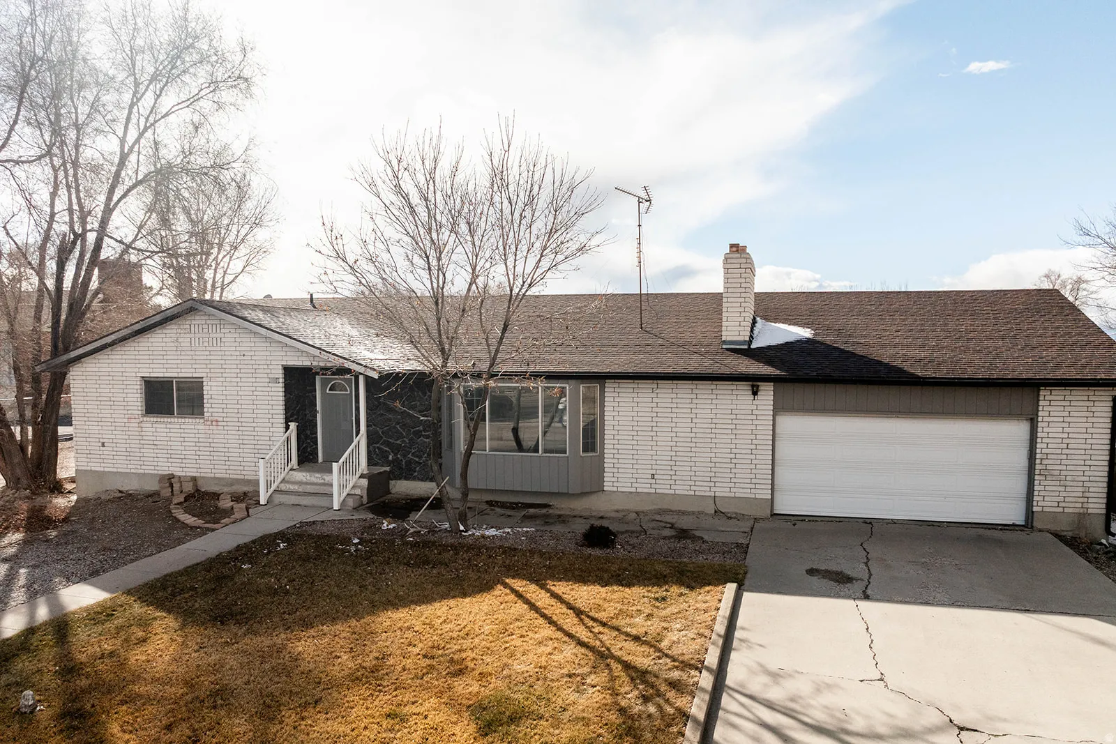 Ranch-style house with concrete driveway, a chimney, a garage, brick siding, and entry steps