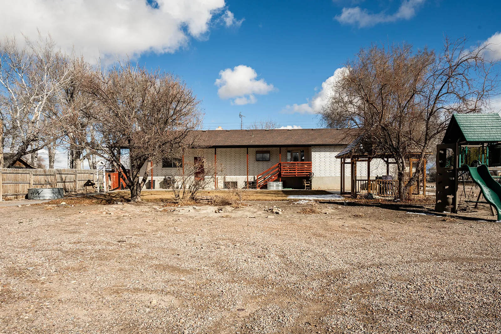 Rear view of house with brick siding, a playground, and a patio