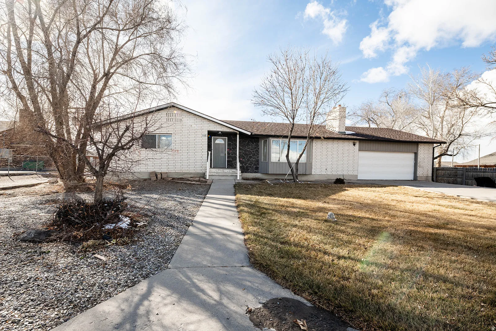 View of front of home featuring brick siding, a garage, a chimney, and concrete driveway