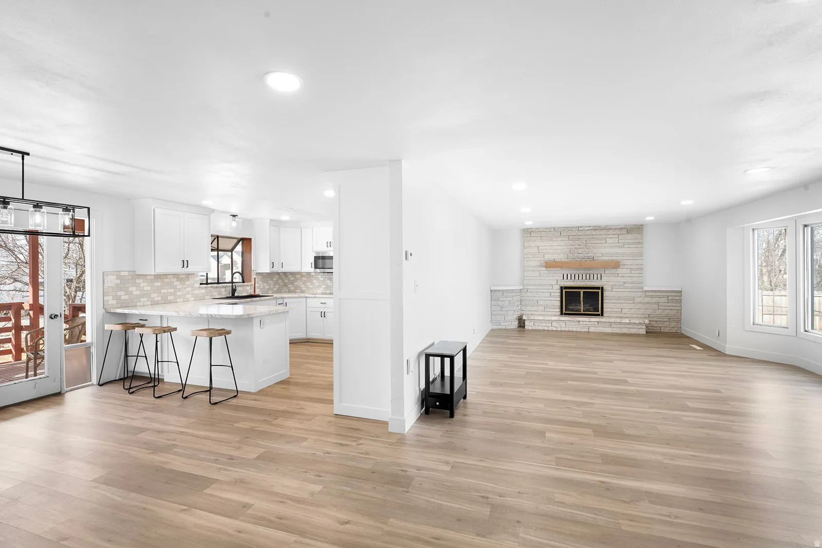 Living room with a fireplace, light wood-type flooring, and recessed lighting
