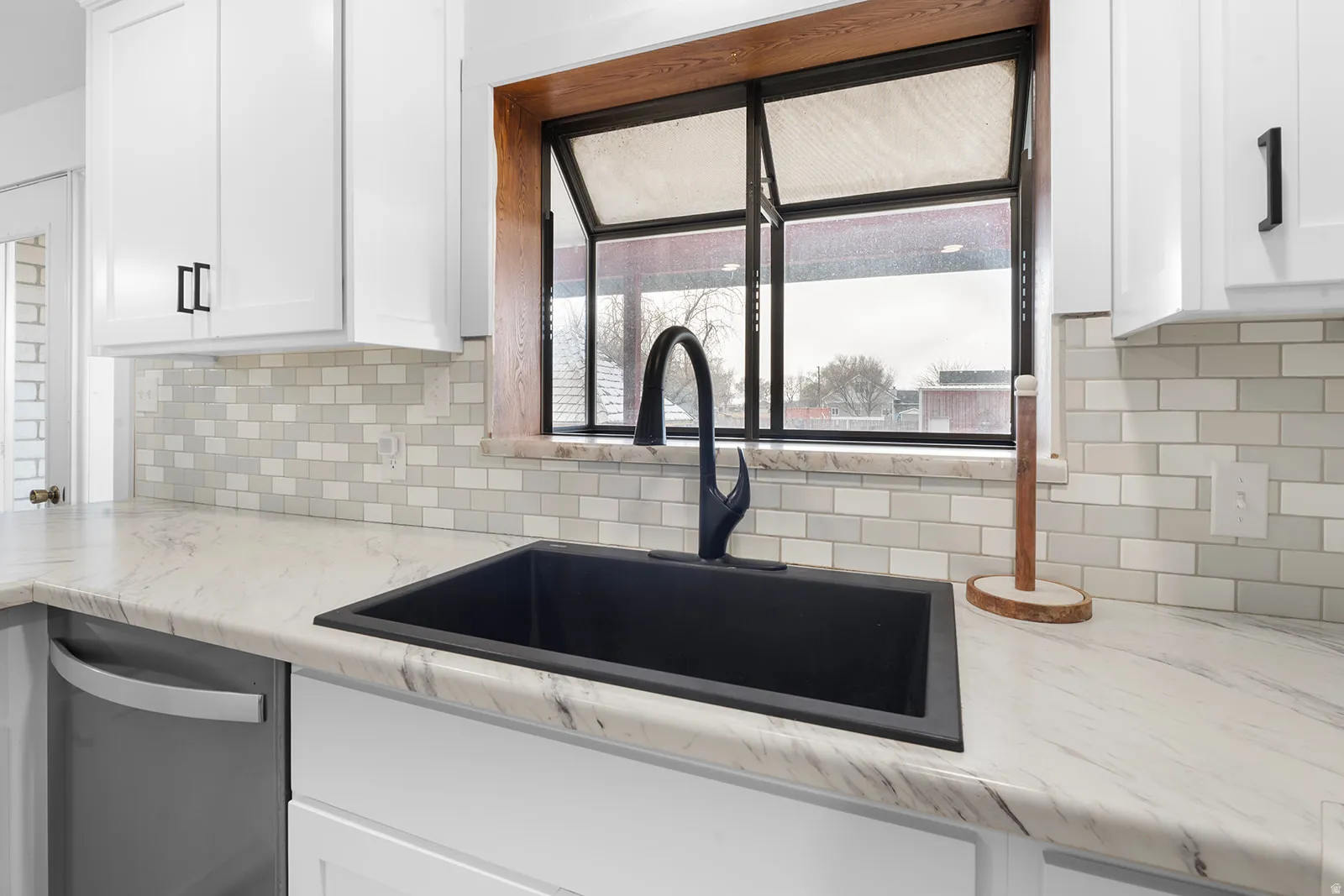 Kitchen with white cabinetry, light stone counters, dishwasher, and decorative backsplash