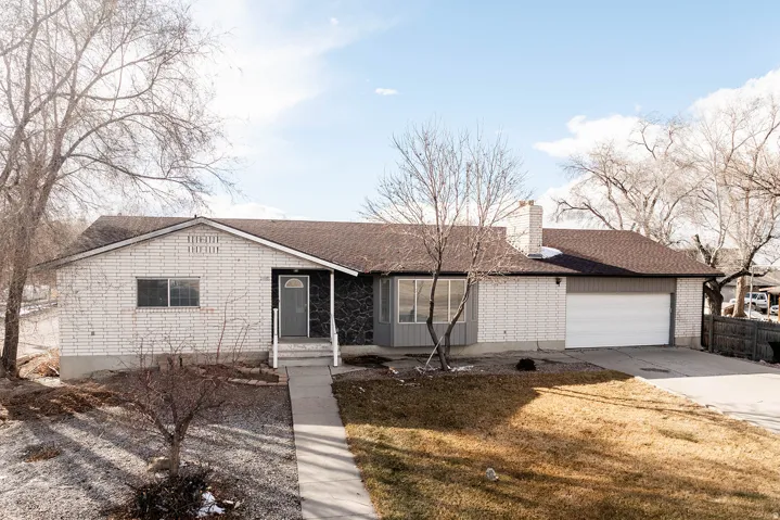 Single story home with driveway, a garage, a chimney, and roof with shingles