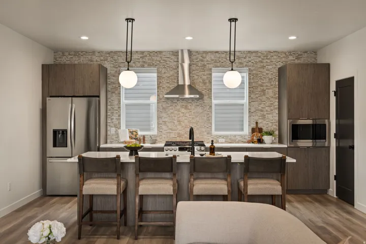 Kitchen with modern cabinets, a kitchen bar, stainless steel appliances, a kitchen island with sink, and hanging light fixtures