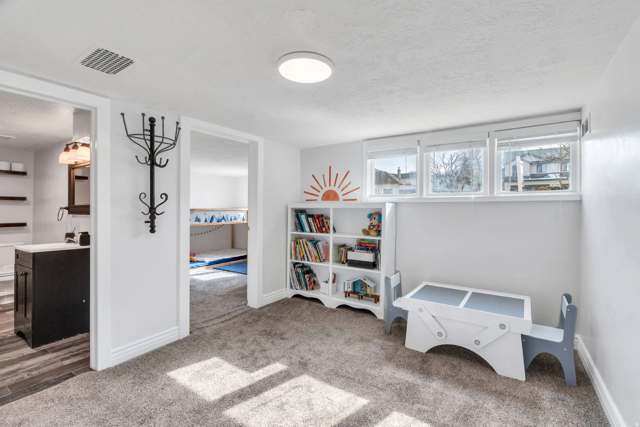 Recreation room with light carpet and a textured ceiling