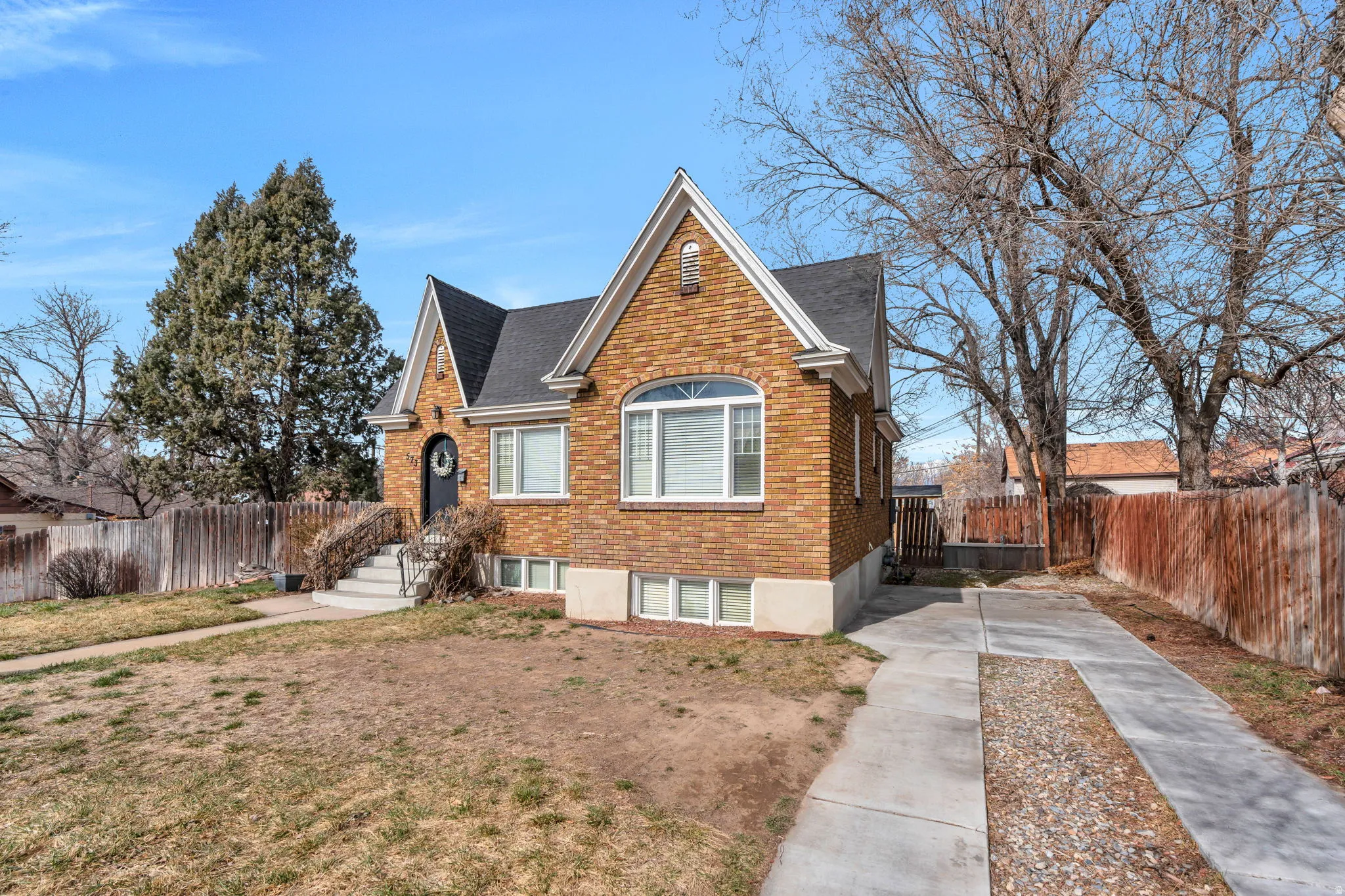 Traditional-style home featuring brick siding, a shingled roof, and concrete driveway