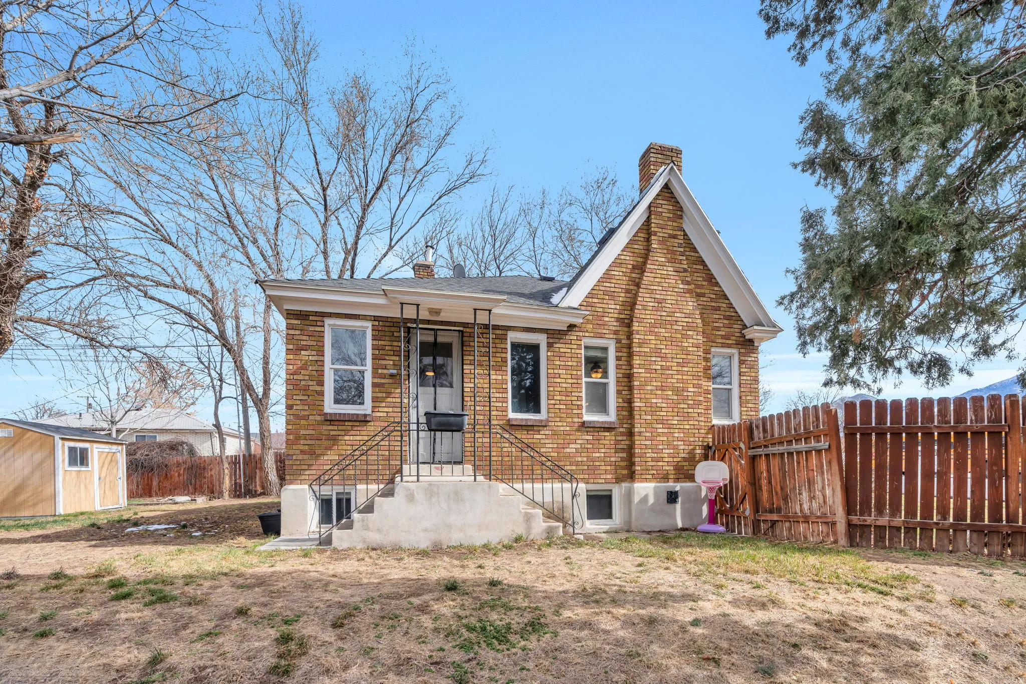 Rear view of house featuring a chimney, brick siding, and an outdoor structure
