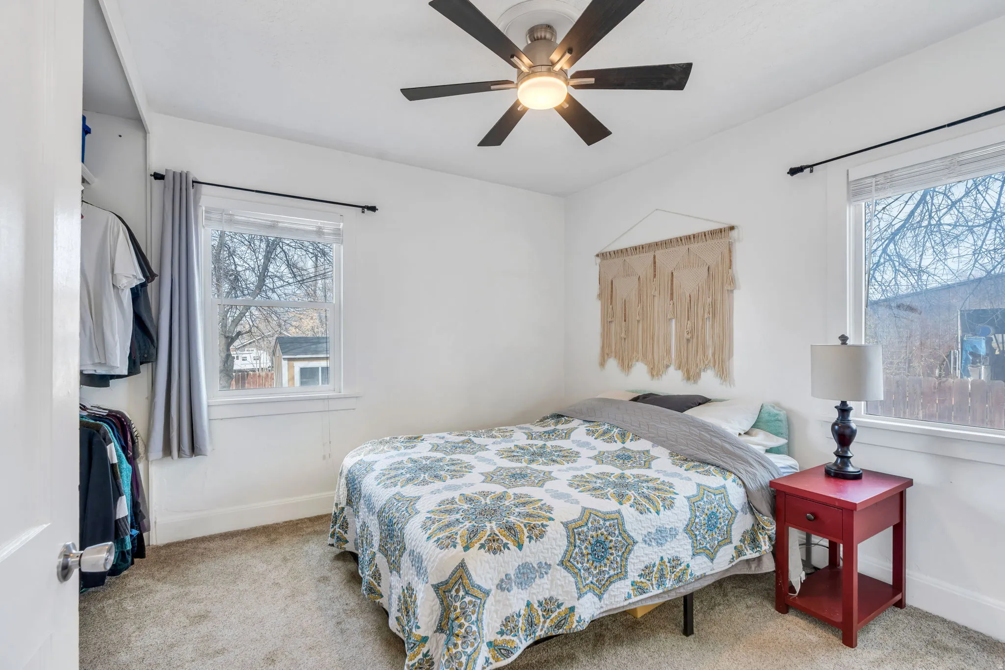 Bedroom with ceiling fan, light carpet, and multiple windows