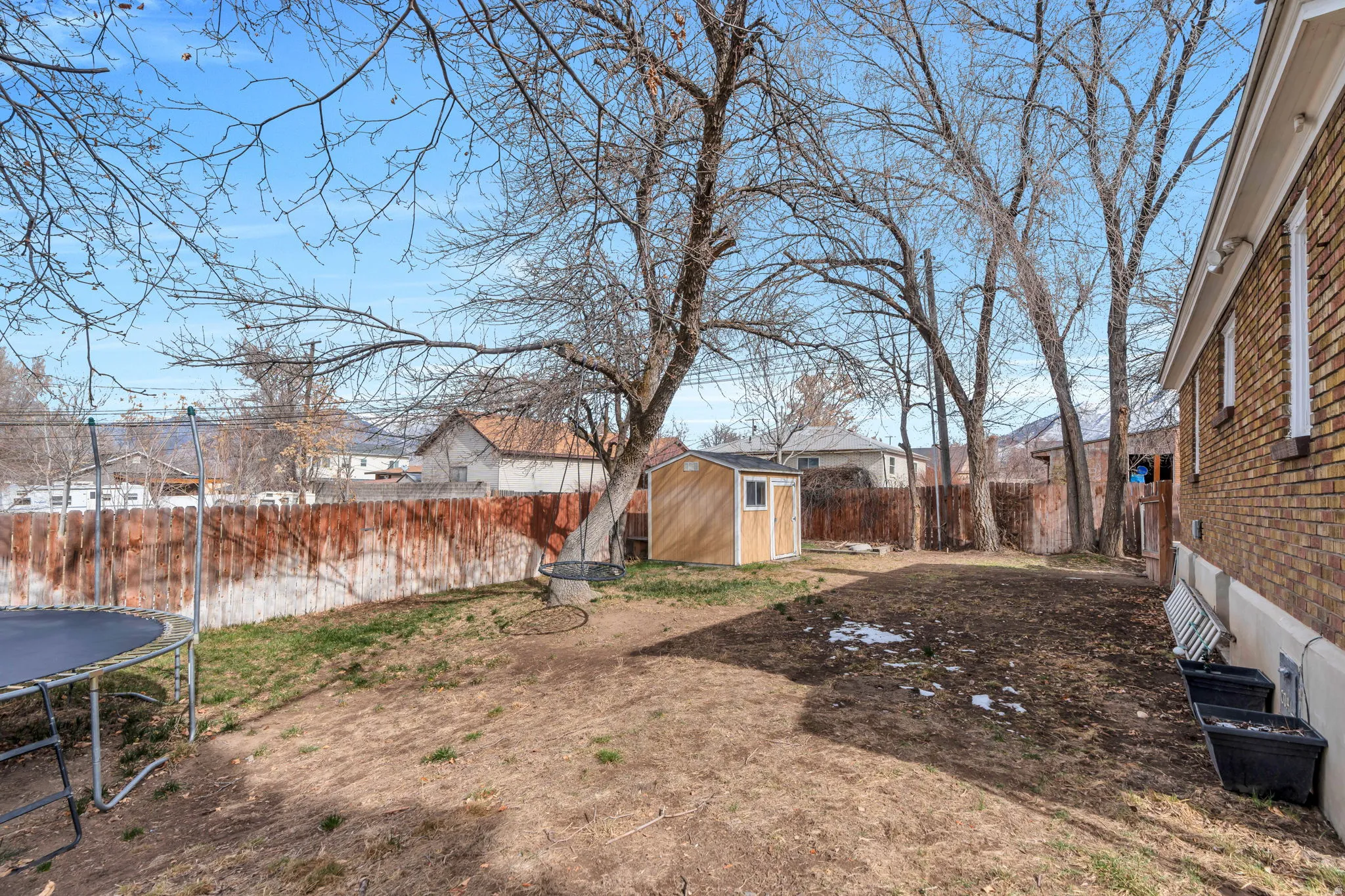 Fenced backyard featuring a shed and a trampoline