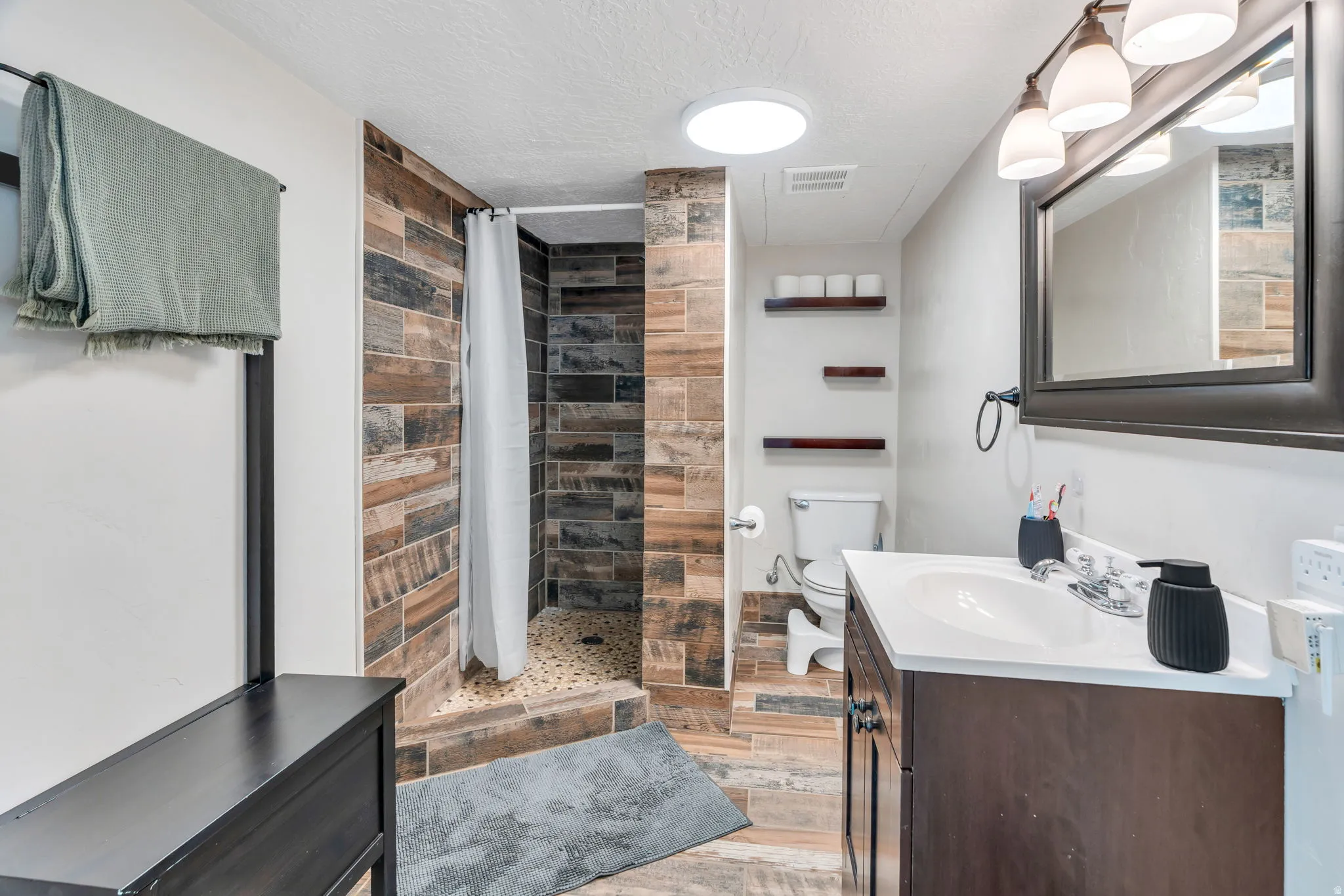Full bathroom featuring vanity, a shower stall, and a textured ceiling