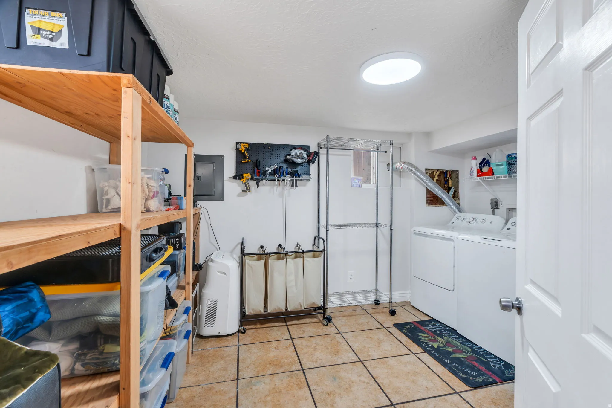 Laundry room with washer and dryer, a textured ceiling, electric panel, and light tile patterned floors