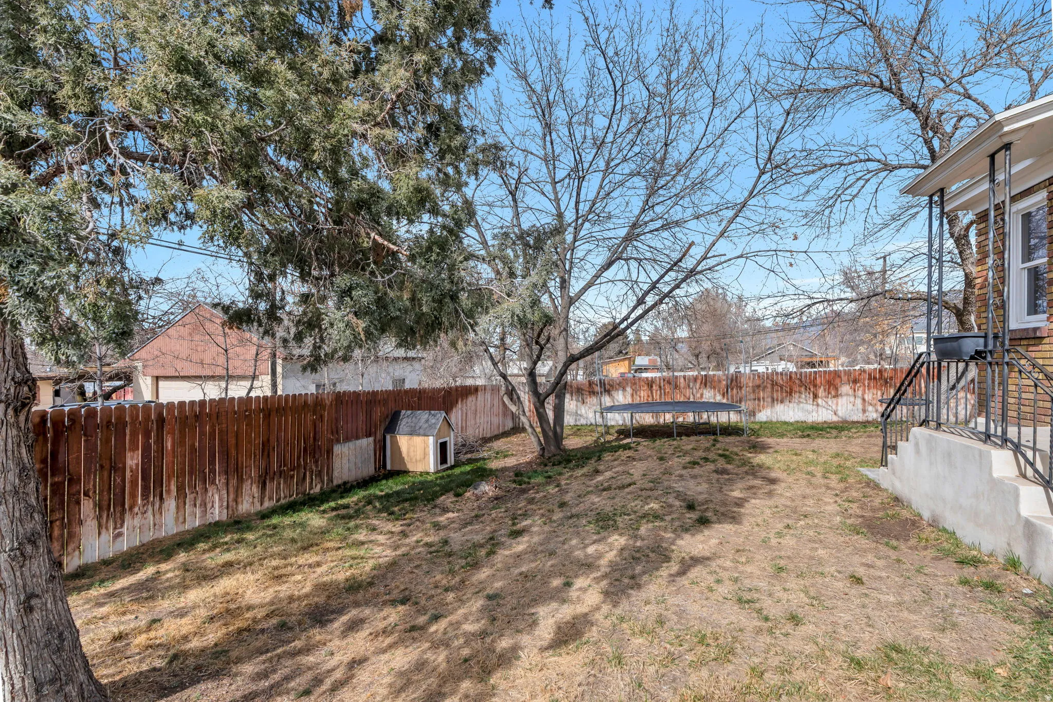 Fenced backyard with a trampoline and a shed