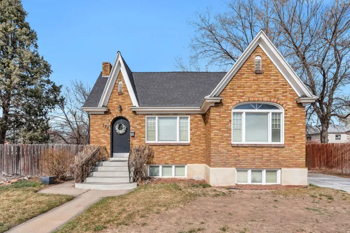 View of front facade featuring brick siding, a chimney, and roof with shingles