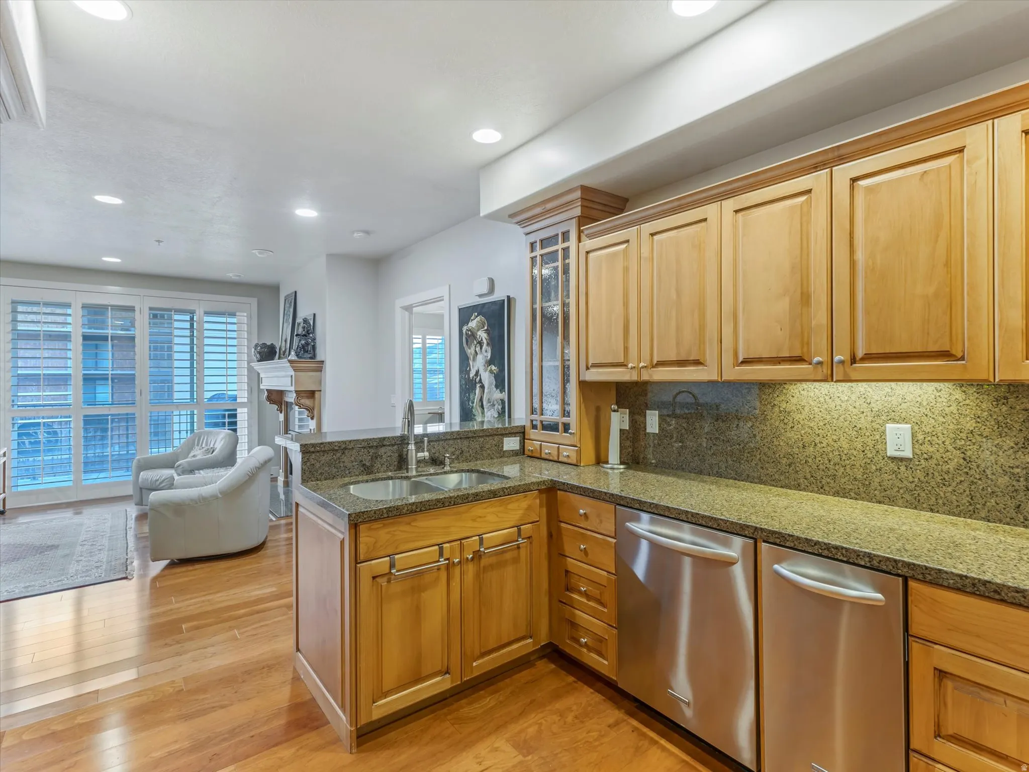 Kitchen with a peninsula, dishwasher, trash compactor, open floor plan, light wood-style floors, and recessed lighting.