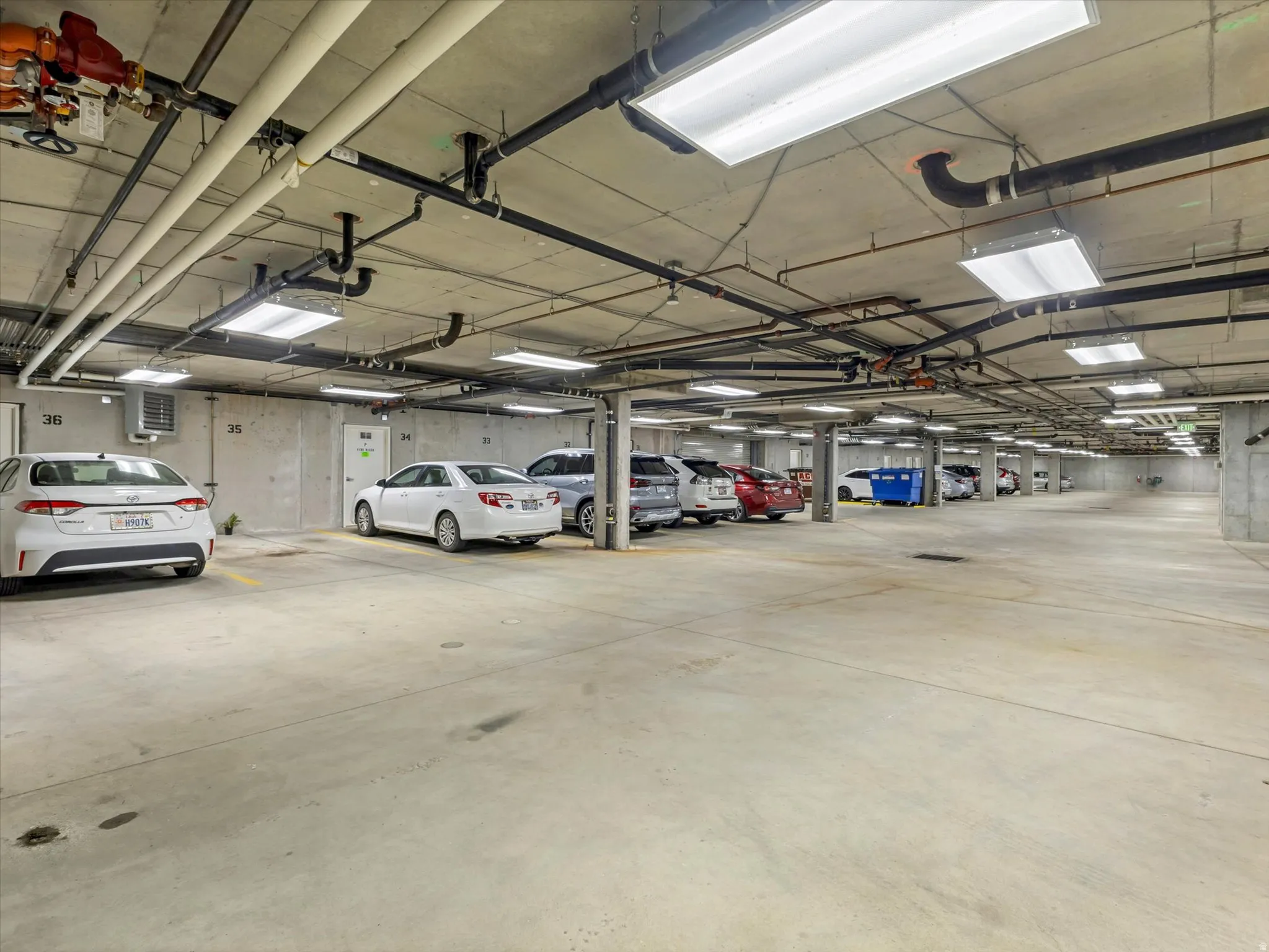 Secure, single-level parking garage featuring a heating unit, security cameras, trash and recycling bins.